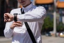 Seção média de homem verificando o tempo enquanto caminha na rua — Fotografia de Stock