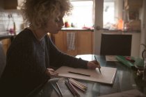 Junge Frau zeichnet Skizze zu Hause — Stockfoto