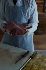 Mittlerer Teil der Metzgerei hält Fleisch in der Hand — Stockfoto