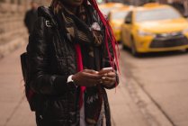 Средняя часть женщины, использующая мобильный телефон на городской улице — стоковое фото