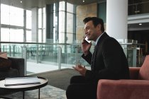 Un uomo d'affari sorridente che fa gesti mentre parla al telefono — Foto stock
