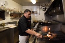 Cuoco maschio che cucina carne al barbecue in cucina — Foto stock