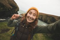 Retrato de una senderista sonriente divirtiéndose cerca del mar - foto de stock