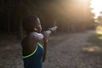 Спортсменка, занимающаяся в лесу упражнениями на растяжку — стоковое фото