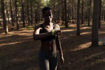 Atleta donna che controlla il suo smartwatch nella foresta — Foto stock