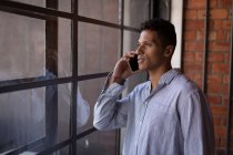 Чоловік розмовляє по мобільному телефону біля вікна вдома — стокове фото