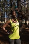 Sportlerin mit Wasserflasche macht Pause im Wald — Stockfoto