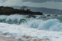 Welle des Meeres stürzt bei dunklem Wetter am Strand ab — Stockfoto