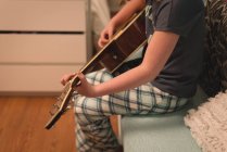 Chica tocando la guitarra en el dormitorio en casa - foto de stock