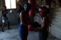 Entrenador que ayuda al joven boxeador masculino en el gimnasio - foto de stock