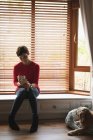 Жінка має каву під час використання мобільного телефону у вітальні вдома — стокове фото