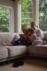 Madre e figli seduti sul divano e utilizzando tablet digitale a casa — Foto stock