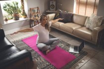 Mujer embarazada haciendo ejercicio en la sala de estar en casa - foto de stock