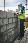 Engenheiro fazendo uma verificação de nível na parede no canteiro de obras — Fotografia de Stock