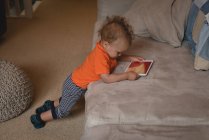 Дитячий хлопчик використовує цифровий планшет на дивані вдома — стокове фото