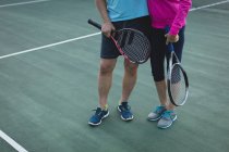 Senioren-Paar steht auf Tennisplatz — Stockfoto
