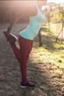 Athlète féminine faisant de l'exercice de jambe dans la forêt — Photo de stock