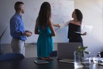 Führungskräfte diskutieren über Whiteboard, während sie Laptop im Büro benutzen — Stockfoto
