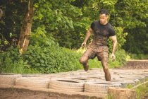 Fit man training over tyres obstacle course at boot camp — Stock Photo