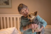 Senior mulher segurando um cão em casa — Fotografia de Stock
