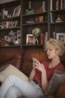 Young woman using mobile phone in living room at home — Stock Photo