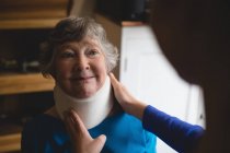 Крупный план физиотерапевта, устанавливающего шейный воротник на пожилую женщину — стоковое фото