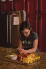 Девушка, использующая мобильный телефон на кухне дома — стоковое фото
