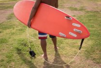 Мужчина-сёрфер держит поводок для серфинга на пляже — стоковое фото