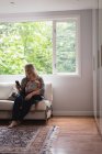 Мати і дитина сидять на дивані і використовують мобільний вдома — стокове фото