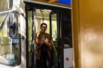 Женщина выходит из автобуса на автобусной остановке — стоковое фото