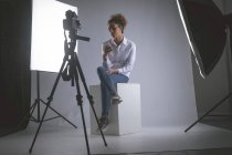 Жінка-фотограф використовує мобільний телефон у фотостудії — стокове фото