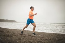 Junger Mann joggt am Strand — Stockfoto