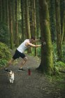 Adatto uomo facendo esercizio di stretching con il suo cane nella foresta — Foto stock