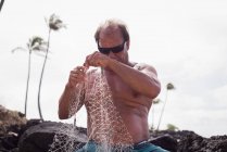 Рыбак держит рыболовные сети на пляже — стоковое фото