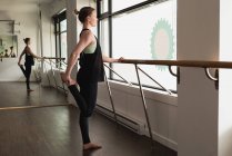 Junge Frau mit einem Bein beim Dehnen im Fitnessstudio — Stockfoto