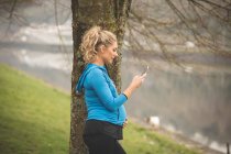 Красивая беременная женщина с помощью мобильного телефона в парке — стоковое фото