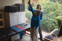 Fisioterapeuta auxiliando uma mulher idosa com exercícios de fisioterapia — Fotografia de Stock