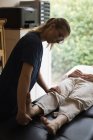 Фізіотерапевт дає масаж ноги літній жінці вдома — стокове фото