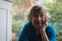 Крупним планом щаслива старша жінка дивиться на камеру вдома — стокове фото