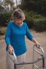 Старшая женщина, идущая с помощью ходунков — стоковое фото