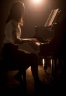 Side view of schoolgirl playing piano in music school — Stock Photo