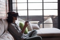 Frau spielt Videospiel mit Virtual-Reality-Headset zu Hause — Stockfoto