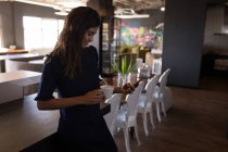 Empresária usando telefone enquanto toma café no refeitório do escritório — Fotografia de Stock