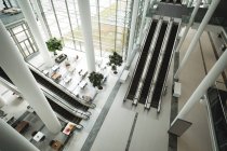 Vista de alto ângulo de escadas rolantes e pilares no escritório — Fotografia de Stock