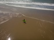 Высокий угол зрения серфера с доской для серфинга ходьба по пляжу — стоковое фото