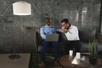 Zwei Geschäftsleute trinken Kaffee und diskutieren am Laptop — Stockfoto