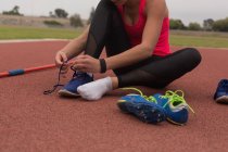 Athlète féminine attachant des lacets sur le site de sport — Photo de stock