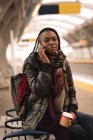Молодая женщина разговаривает по мобильному телефону на вокзале — стоковое фото