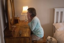 Donna anziana che si guarda allo specchio in camera da letto — Foto stock