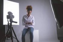 Fotógrafa feminina usando telefone celular no estúdio de fotografia — Fotografia de Stock
